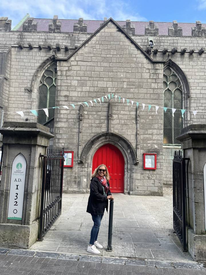 Personne debout devant un bâtiment en pierre grise avec une porte rouge.