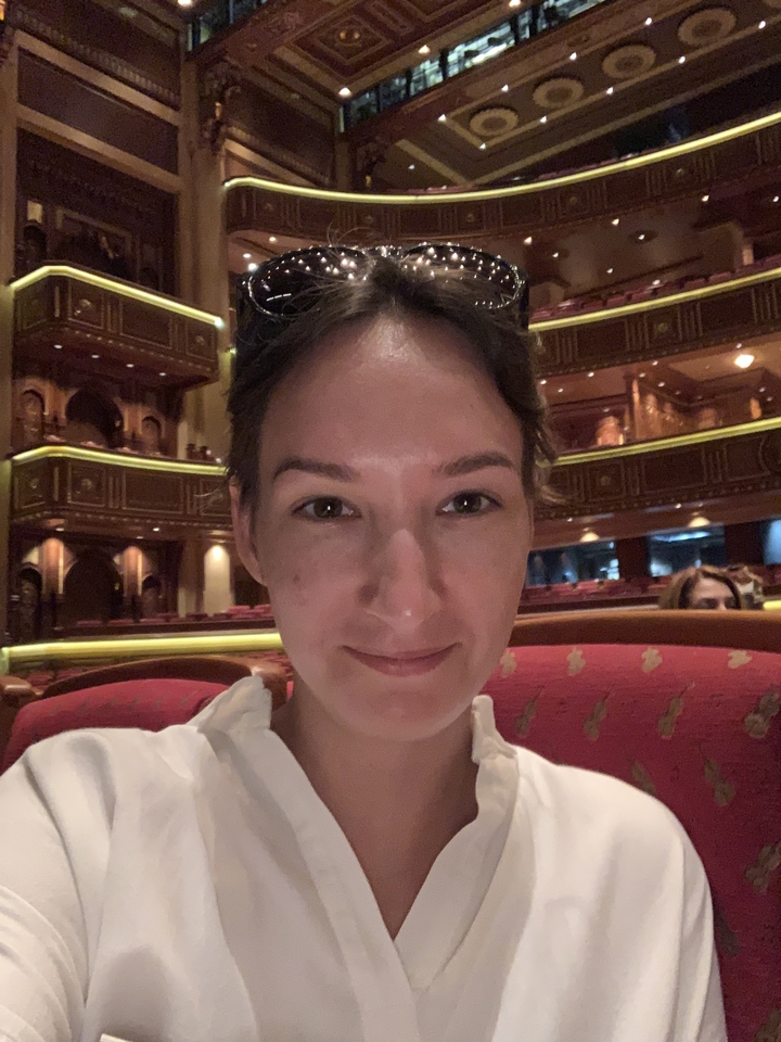 Woman sitting inside an ornate interior setting.