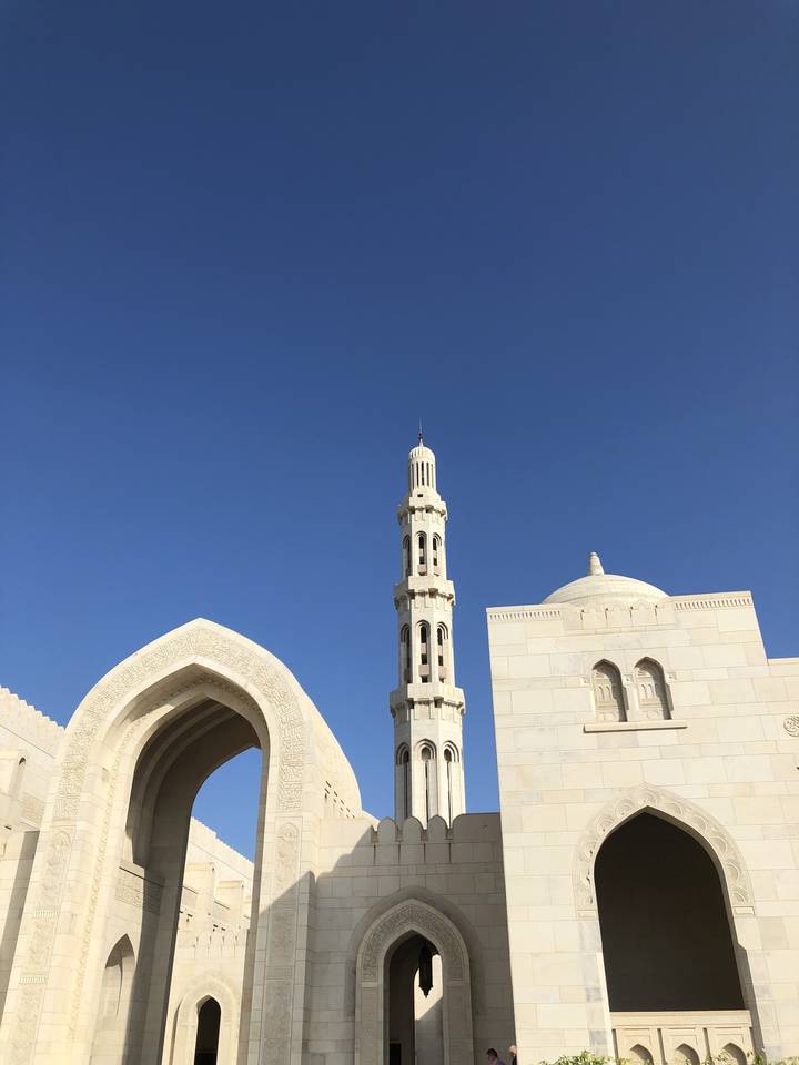 Grand mosque with a tall minaret and blue sky.