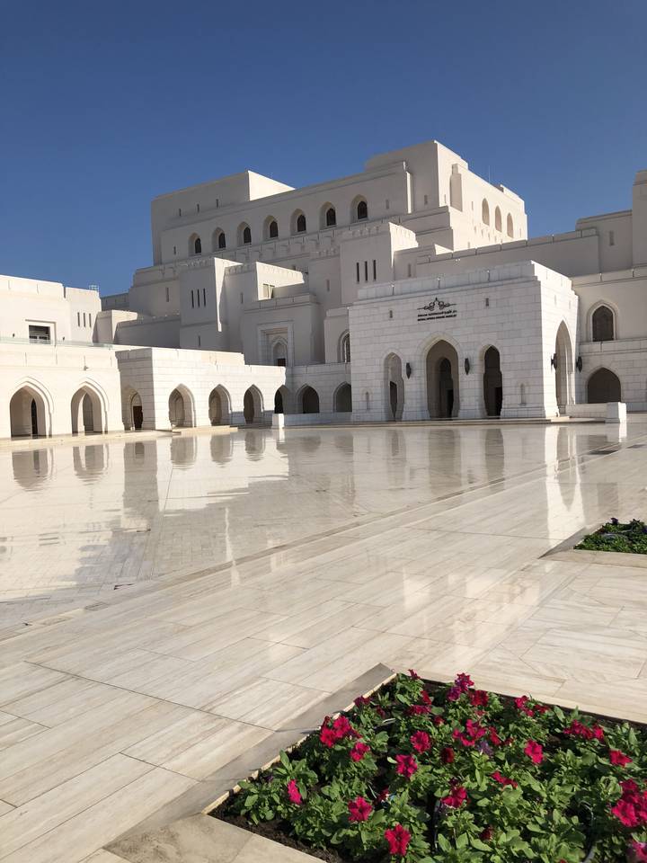 White mosque with intricate architecture and flowers.