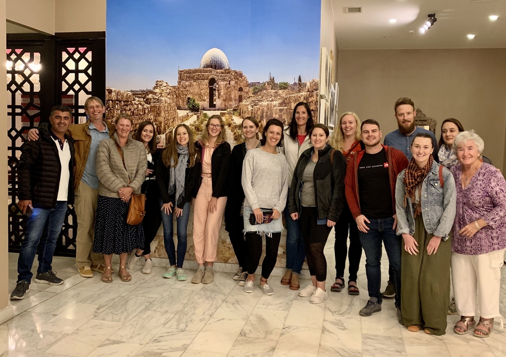 Group photo in an indoor setting with a backdrop of ancient ruins.