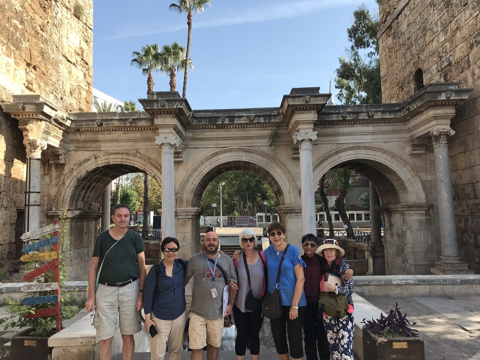 Groupe devant des arches de pierre anciennes.
