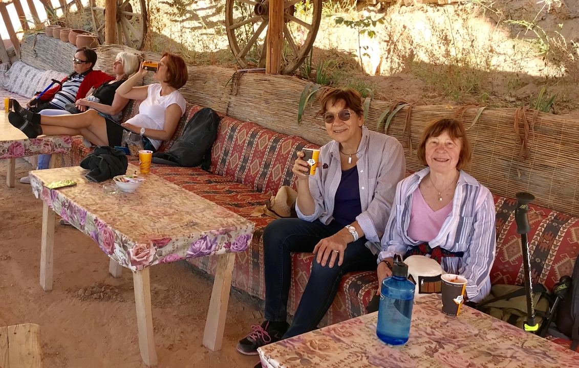Des gens se détendent sur des bancs décorés dans une zone ombragée.