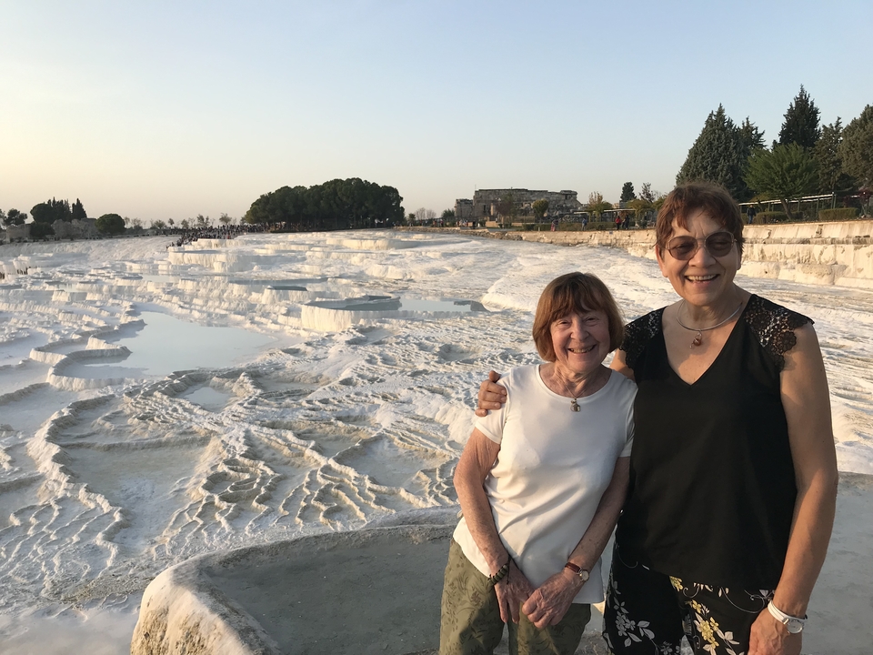 Deux femmes debout devant les terrasses de travertin de Pamukkale.