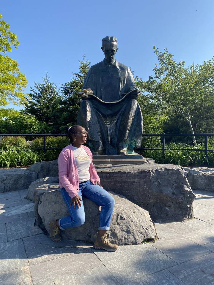 Personne assise avec une statue à l'extérieur.