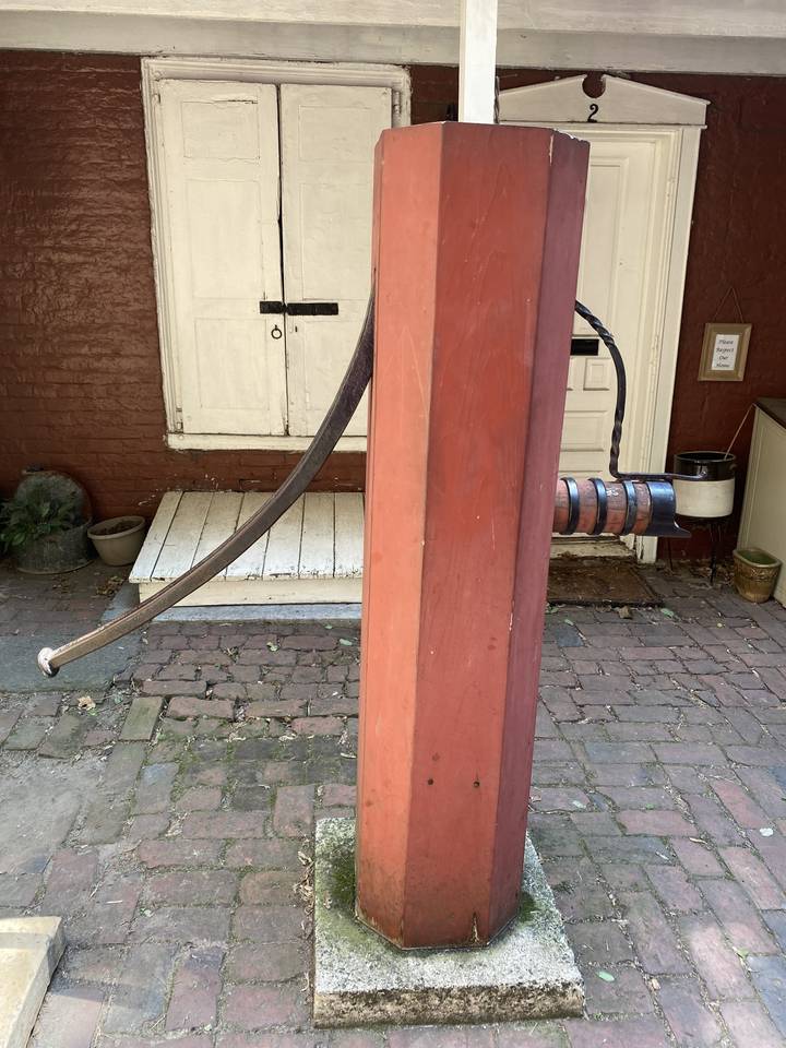 Structure en bois avec une partie d'arche métallique, possiblement une ancienne pompe.
