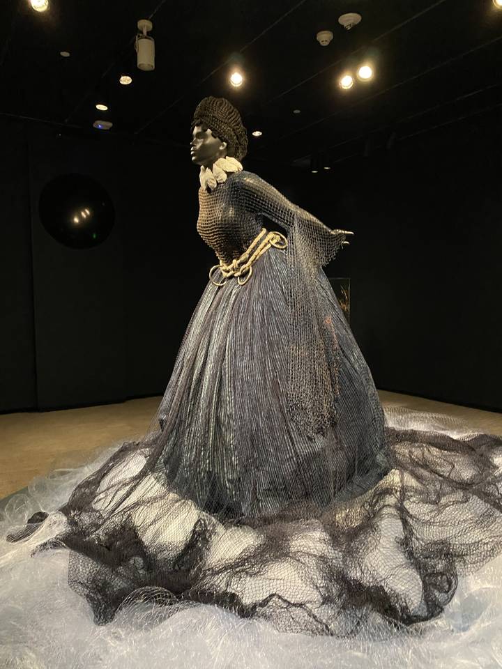 Mannequin artistique portant une robe faite de filet et de fils.