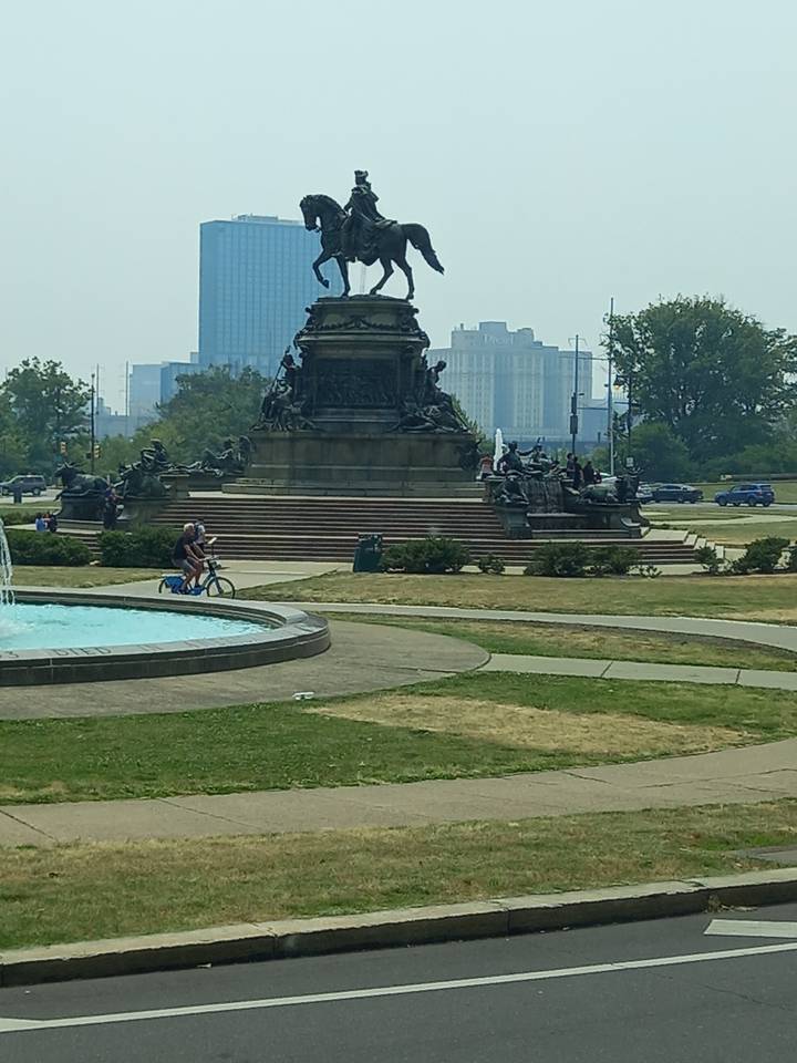 Statue et fontaine avec l'horizon de la ville en arrière-plan.