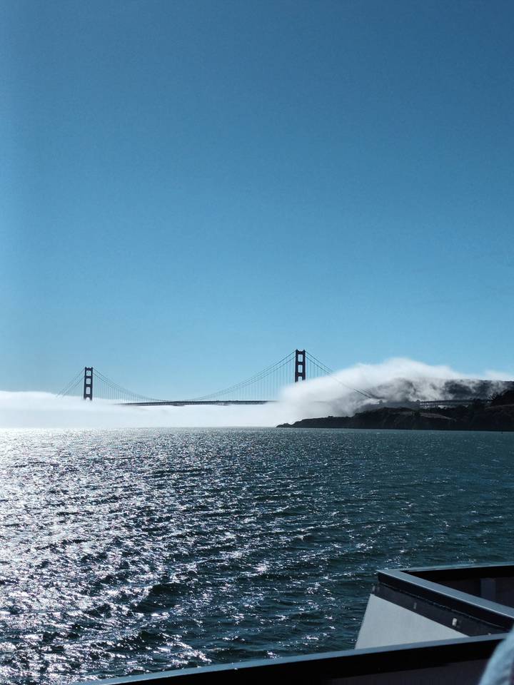 Pont du Golden Gate partiellement obscurci par le brouillard au-dessus d'un plan d'eau scintillant.