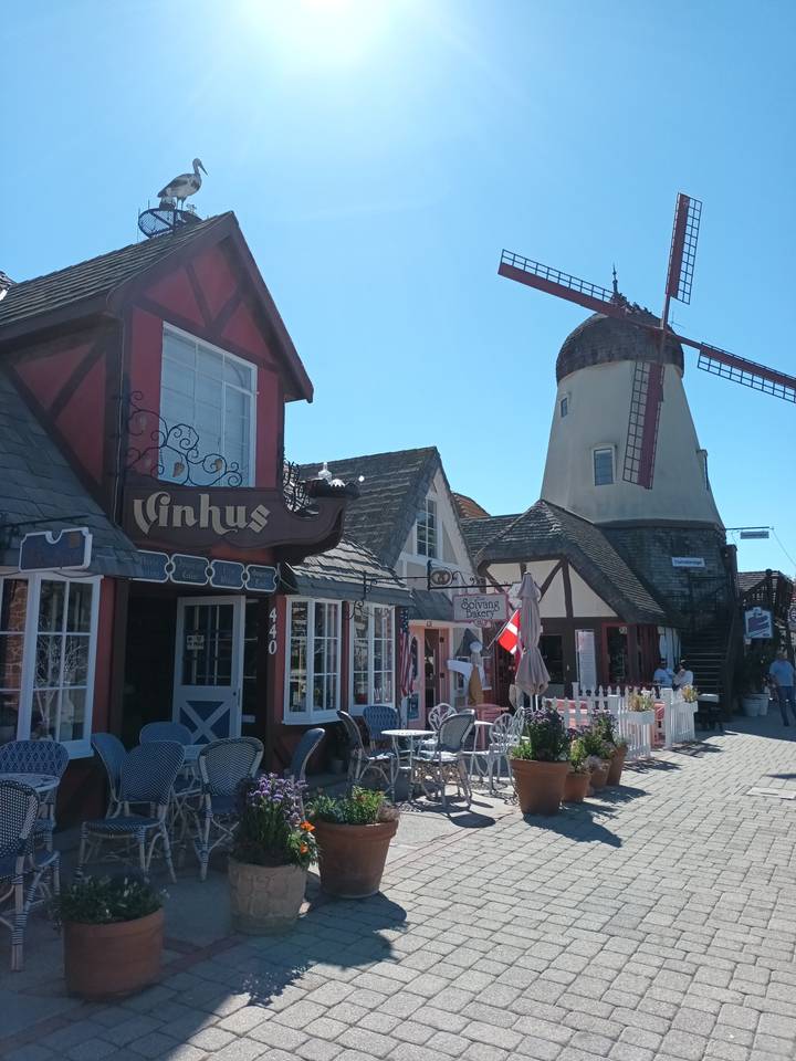 Une charmante rue de style européen avec un moulin à vent et des cafés.