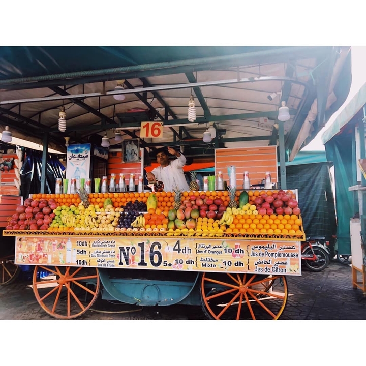 Man selling colorful fruits at a juice stand.
