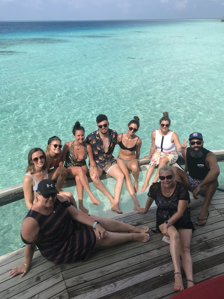 Grupo de amigos sentados sobre el agua en una terraza.