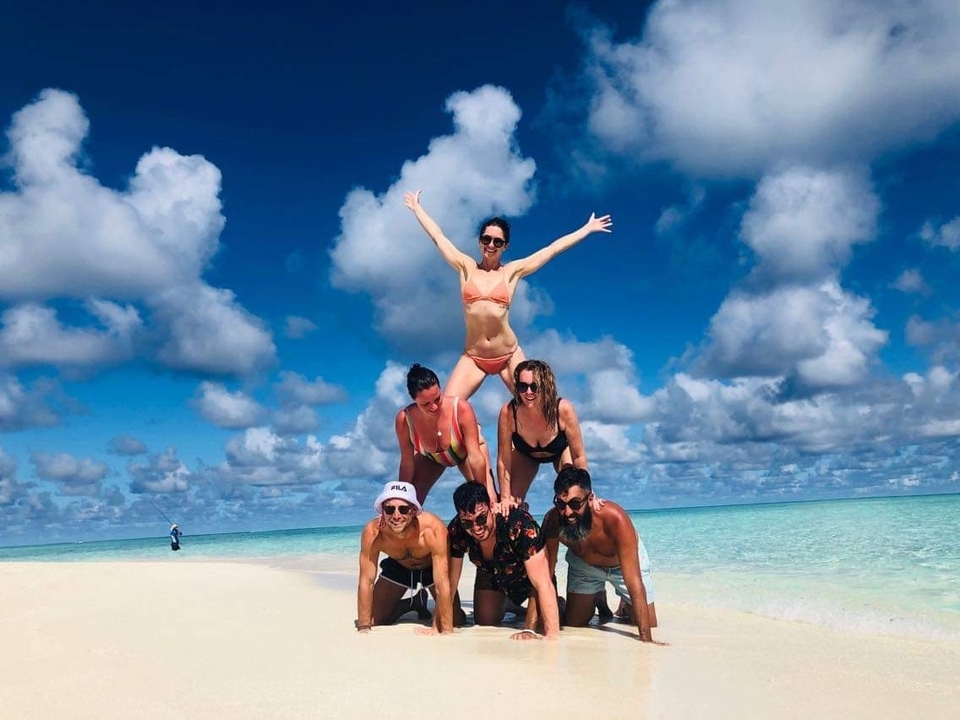 Gente formando una pirámide humana en la playa.