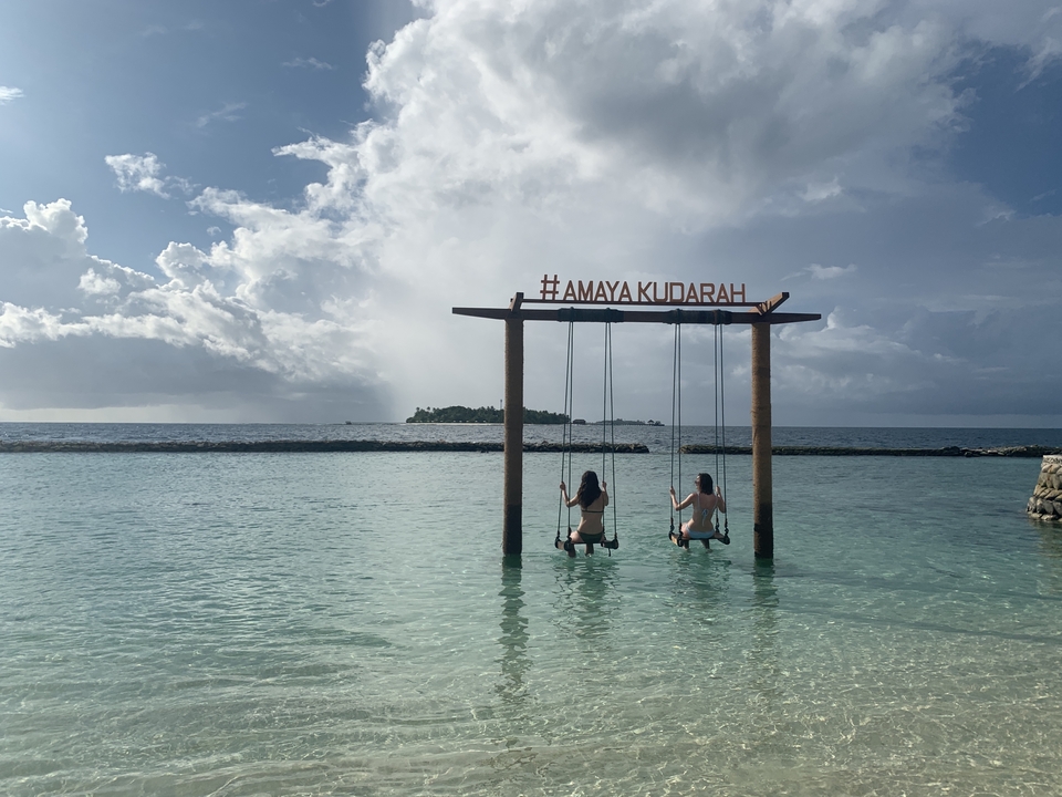 Personas en columpios sobre el océano con vista a la isla.