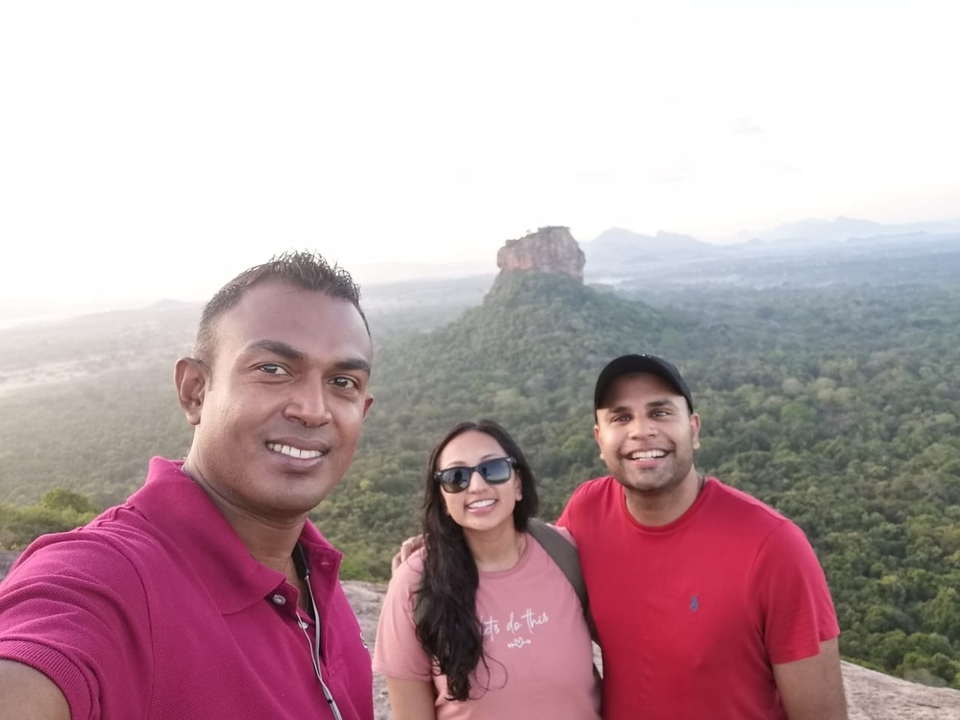 Three people taking a selfie with a distant rock formation in the background.
