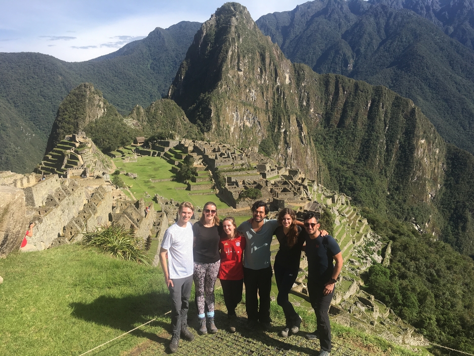A group of people posing at Machu Picchu with the Inca citadel in the background.
