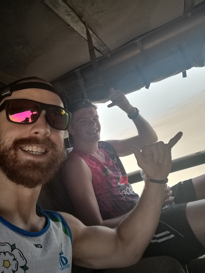 Deux amis souriants qui font des signes de la main à l'intérieur d'un véhicule.