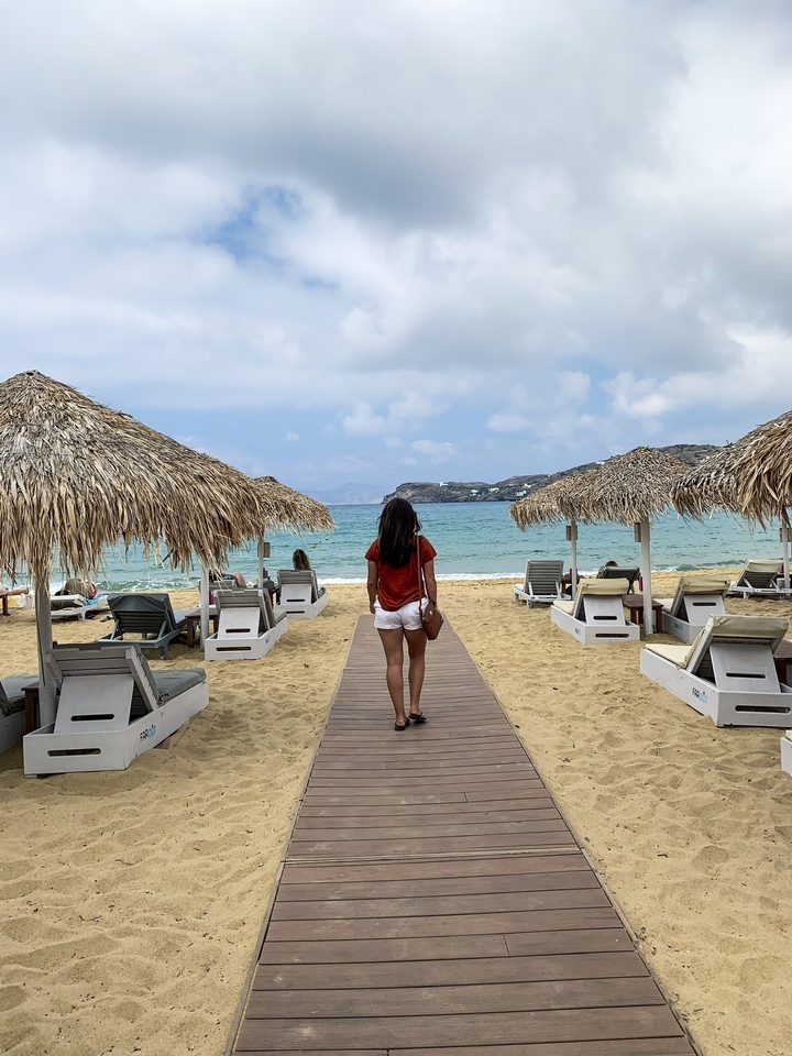 Person walking along a beach walkway towards the sea.