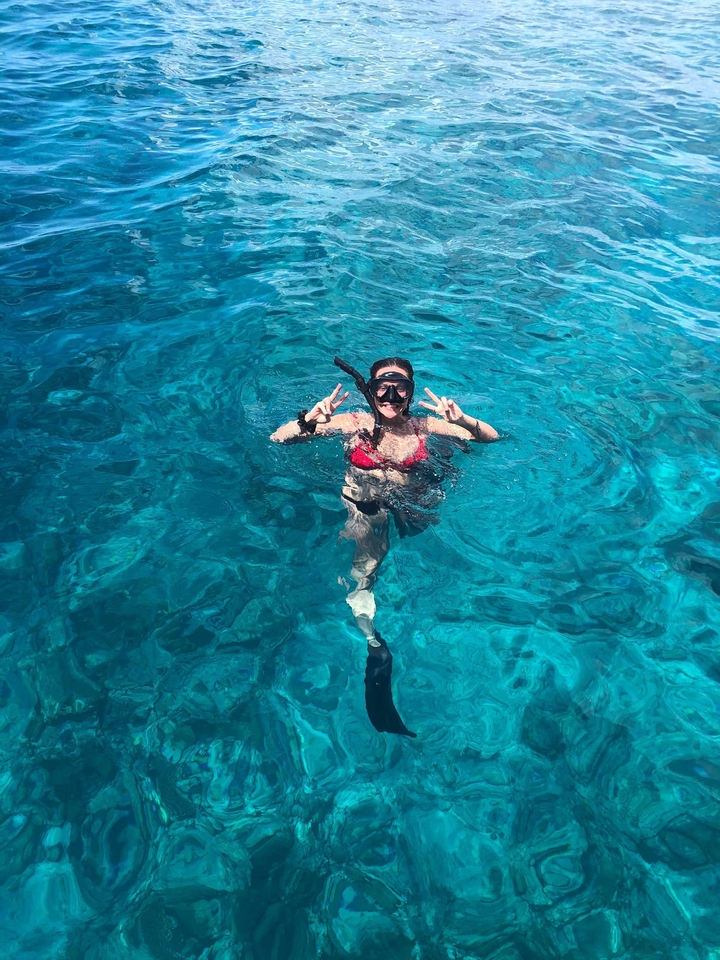 Persona haciendo snorkel y posando en agua azul cristalina.