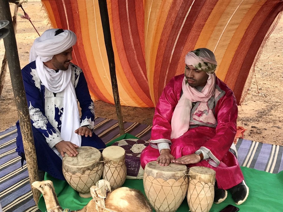 Men in traditional clothing playing drums.
