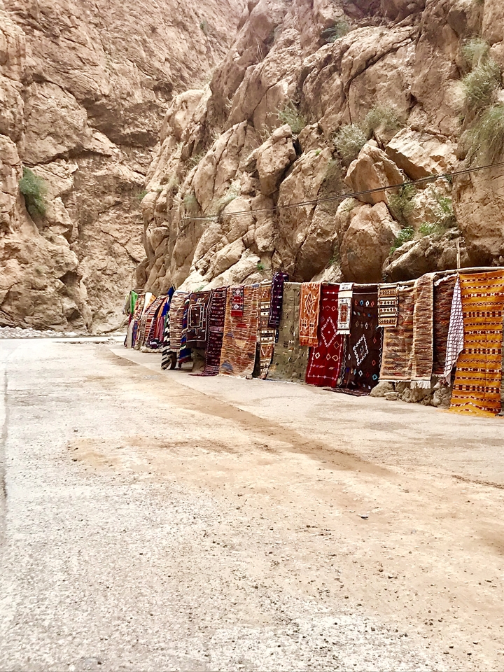 Colorful woven cloths displayed on a rocky mountain.