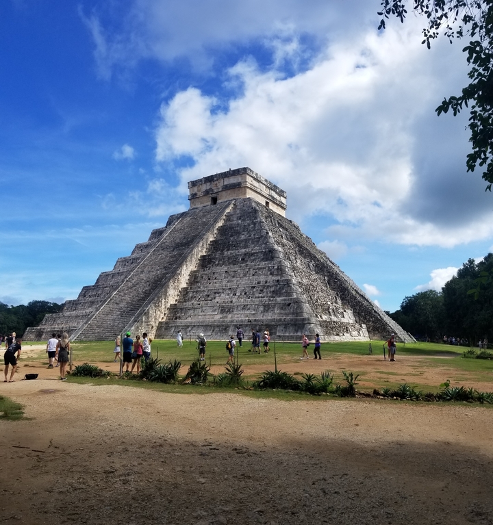 Pyramide de Chichen Itza avec des touristes autour sous un ciel bleu.