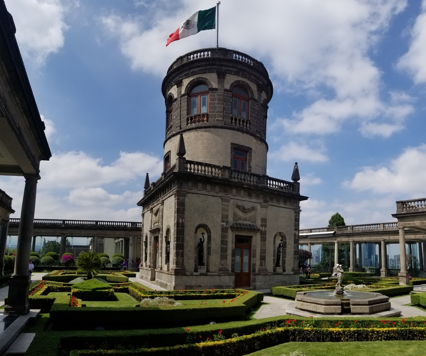 Une tour de pierre historique avec des jardins à la base.