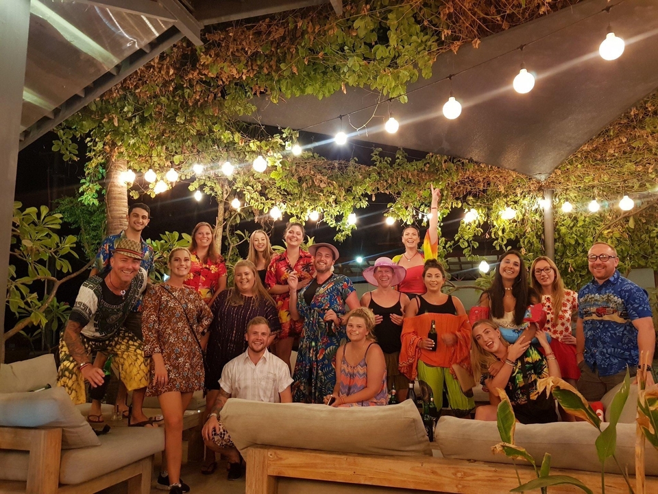 Group of people posing happily under string lights.