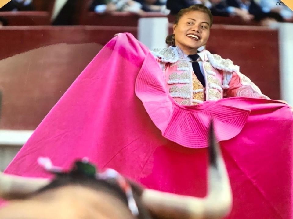 Personne en tenue traditionnelle de matador avec une cape rose.