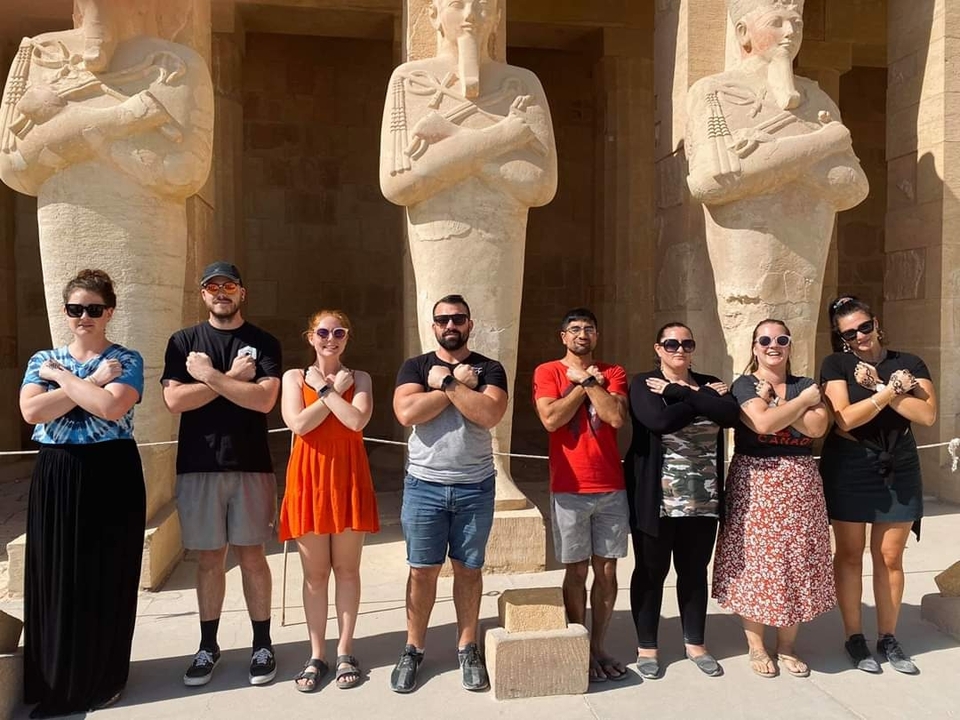 Group of people posing in front of statues at a historic site.
