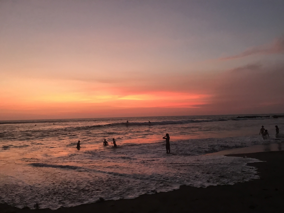 Sunset over the ocean with people in the water