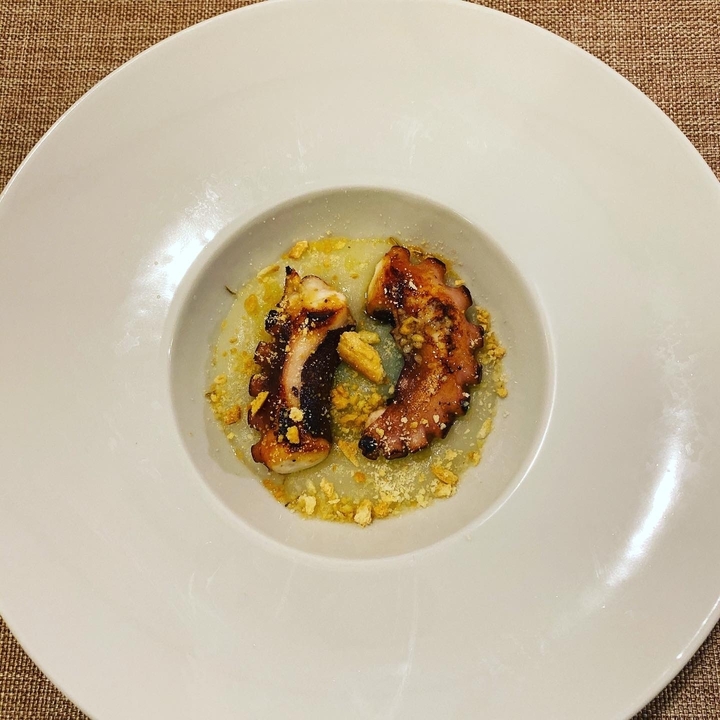 Gourmet dish of octopus on a decorative plate.