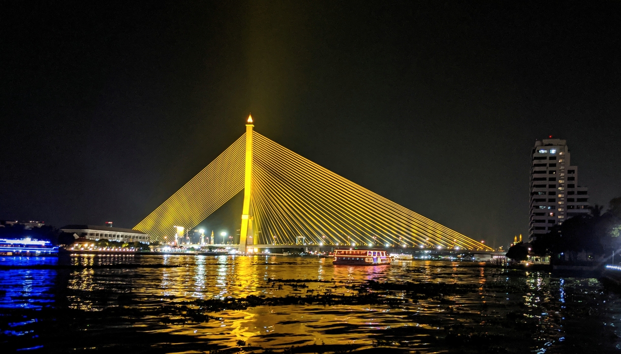 Night view of a brightly lit suspension bridge over water.