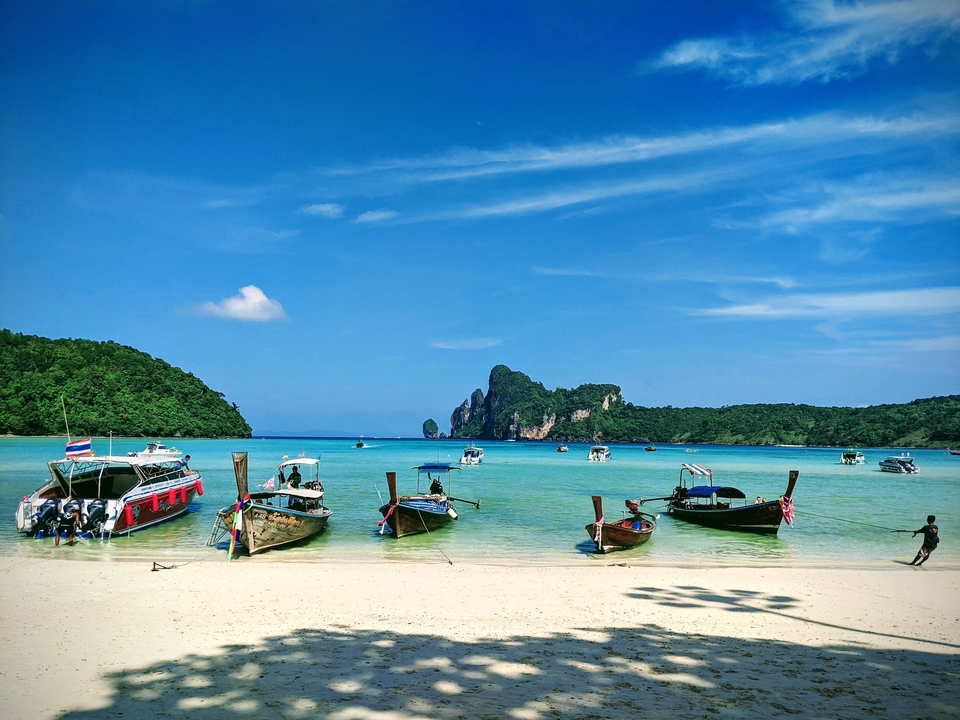 Boats moored on a serene beach with hills in the background.