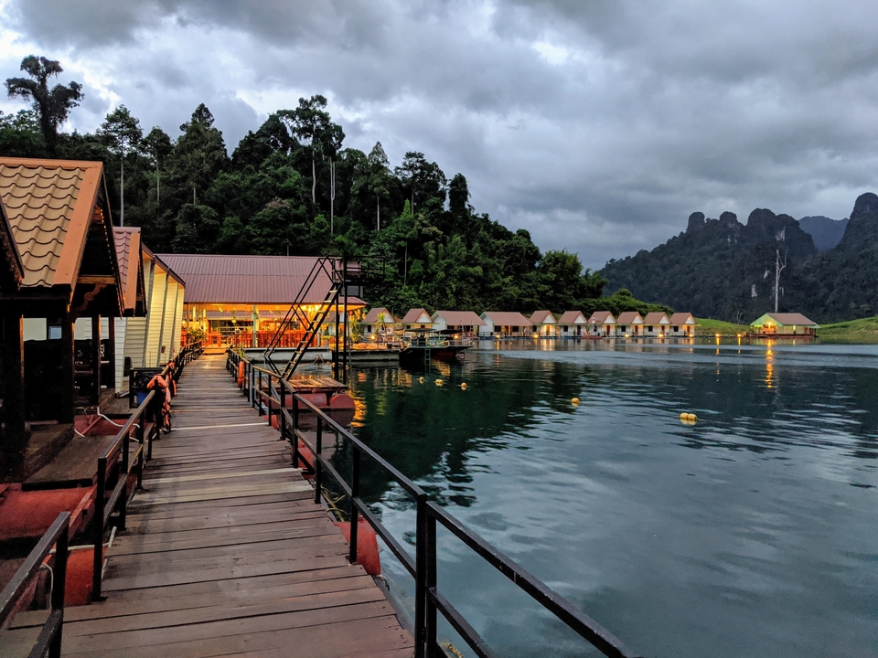 Floating bungalows on a lake surrounded by forested hills.