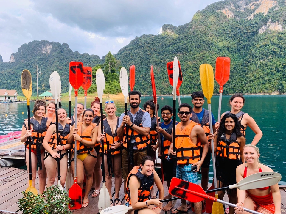 Group posing with paddles at a lakeside dock.
