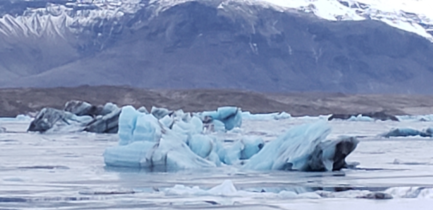 Blue ice formations and mountains in an icy landscape.