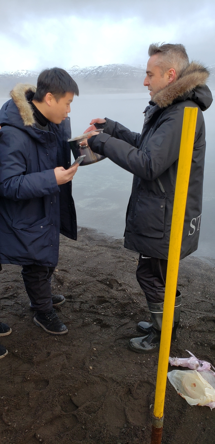 People with a shovel next to a riverbank.