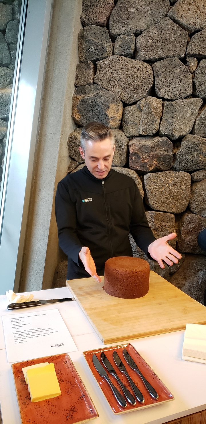 Person presenting a baked item in a rustic interior.