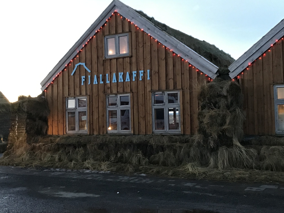A wooden building with a Fjallakaffi sign and festive lights.