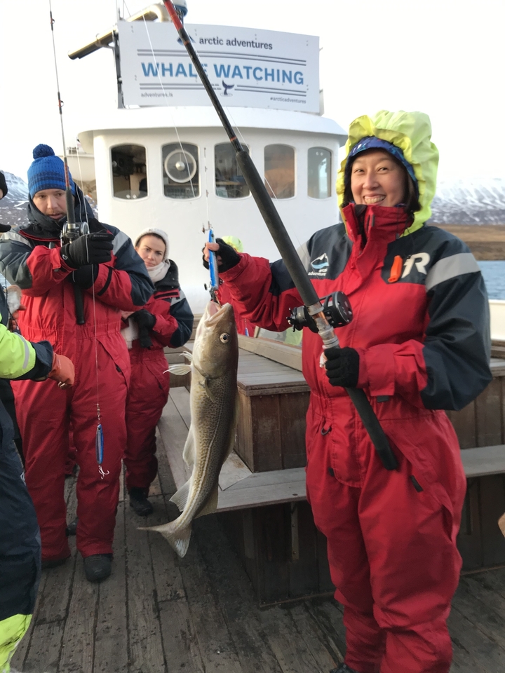 People holding a fish on a fishing boat.