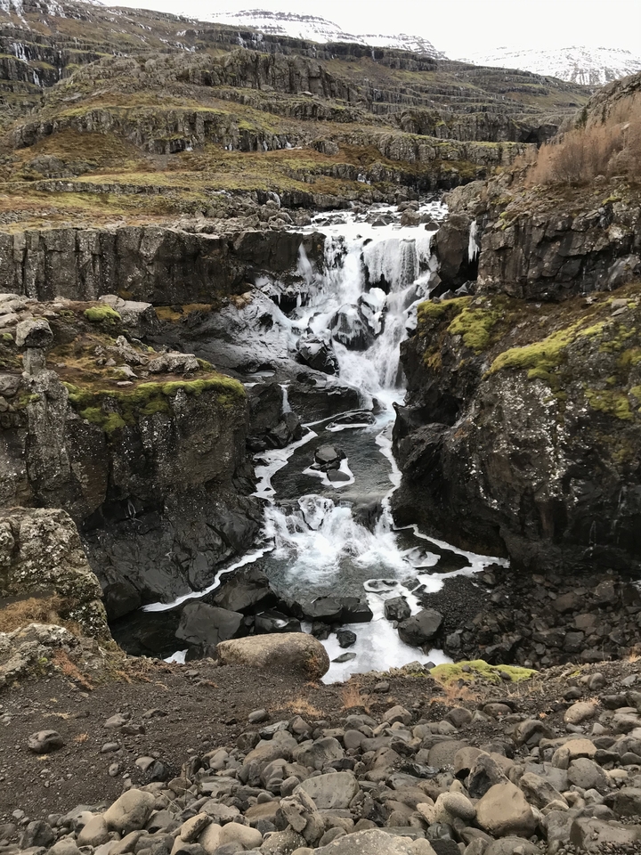 A small cascading waterfall surrounded by rocks and moss.