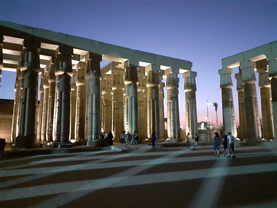 Temple ruins with columns lit at night.