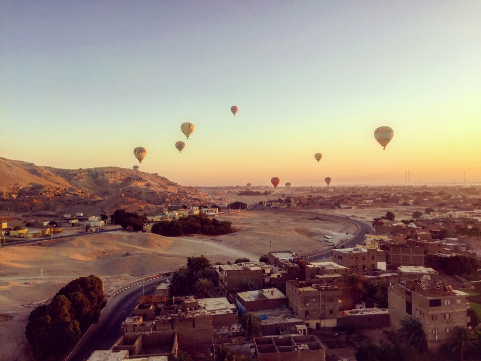 Hot air balloons over a desert landscape during sunrise.