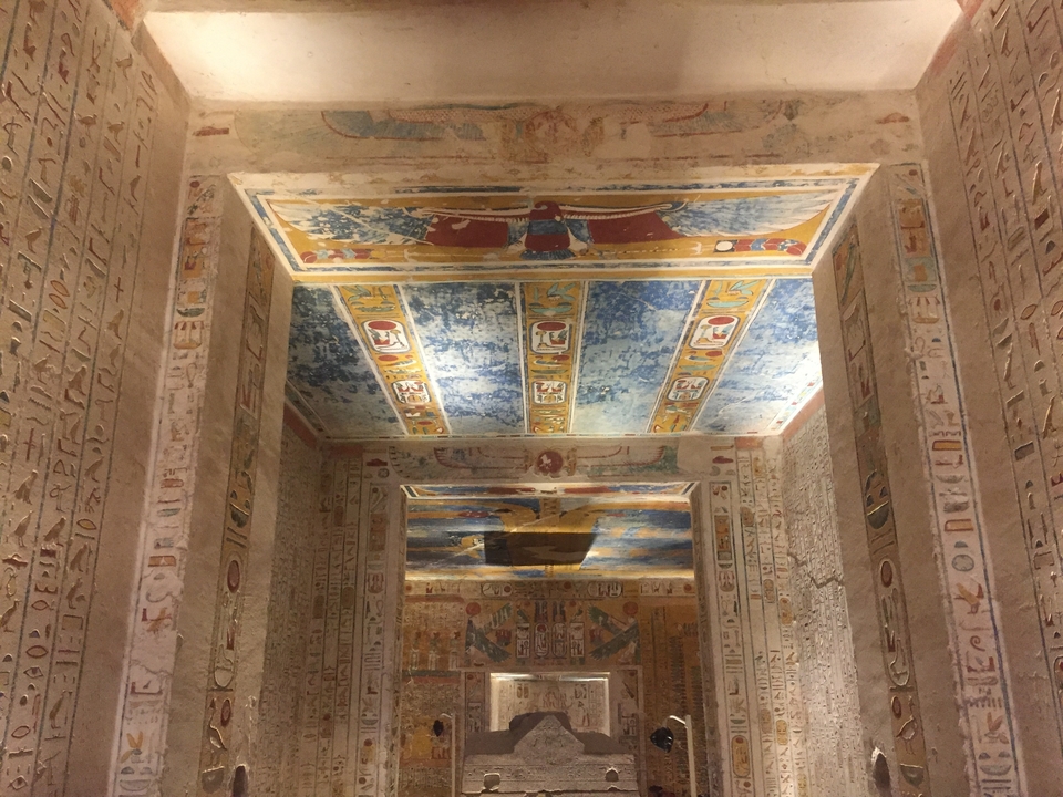 Interior of an ancient temple with colorful hieroglyphics on walls and ceiling.