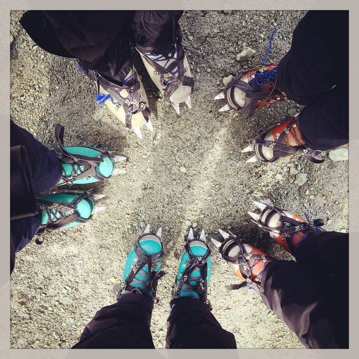 Close-up of people wearing crampons standing on rocky ground.