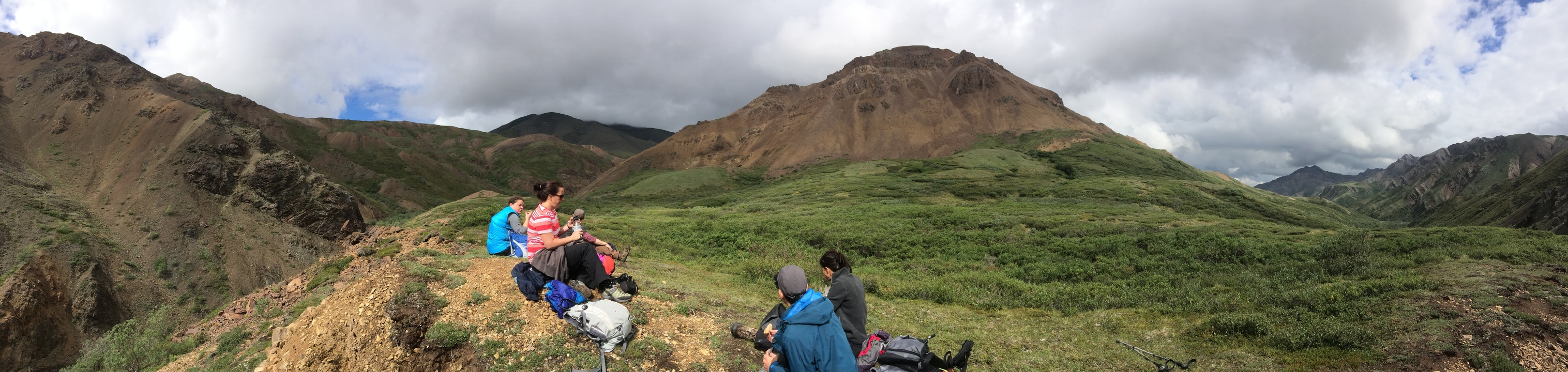Group of people resting on a hillside with a mountain view.