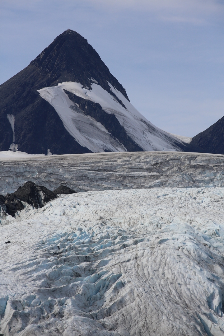 A wide glacier with mountain peaks in the background.