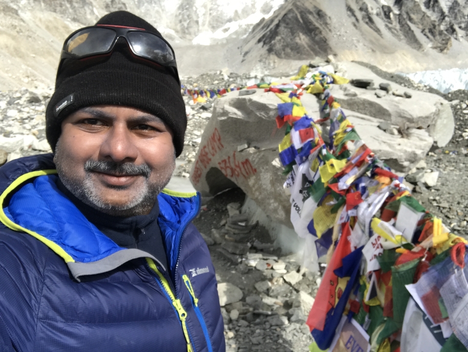 Personne prenant un selfie sur un site avec des drapeaux de prière dans les montagnes.
