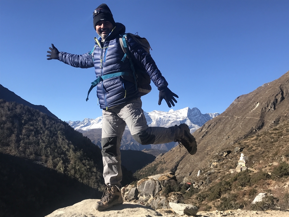 Randonneur sautant avec des montagnes en arrière-plan par une journée claire.